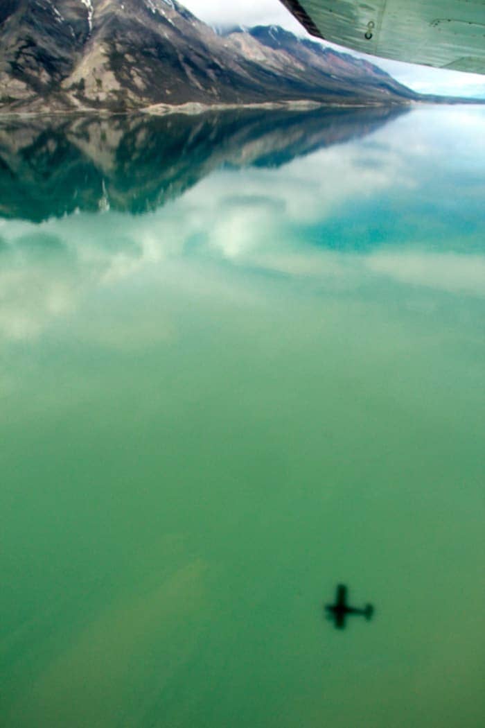 Plane flying over turquoise lake