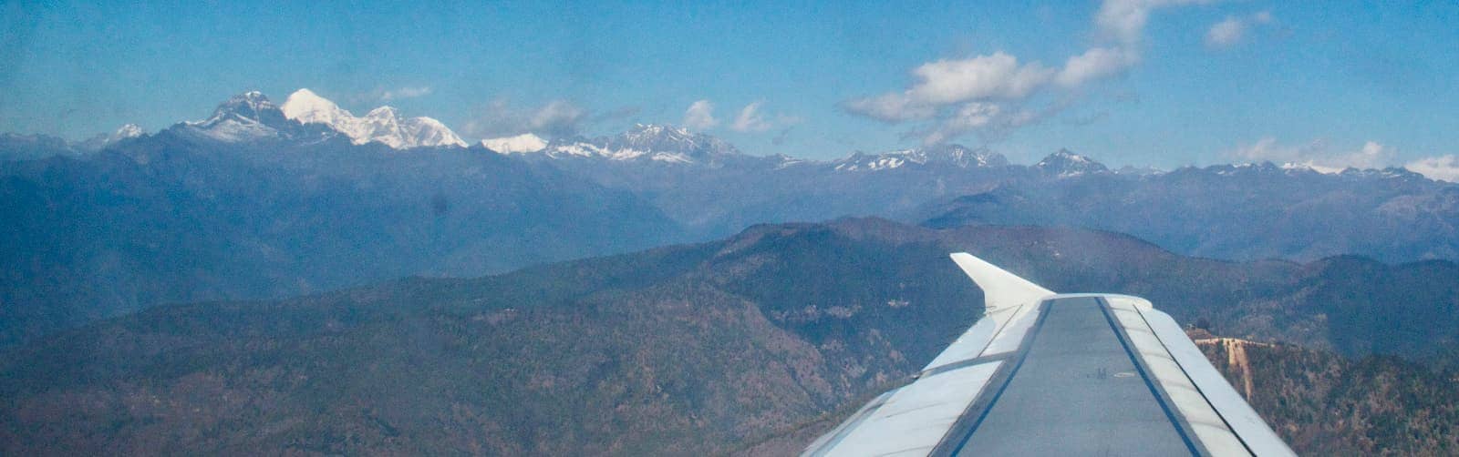 Plane wing in foreground with mountains in background