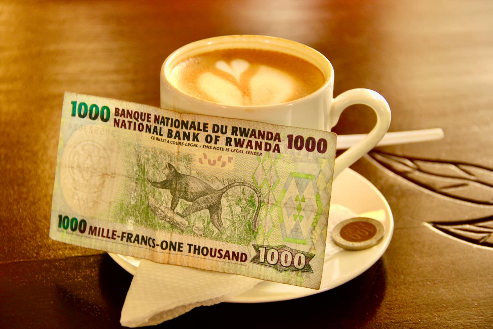 Rwandan bank note placed beside cup of coffee