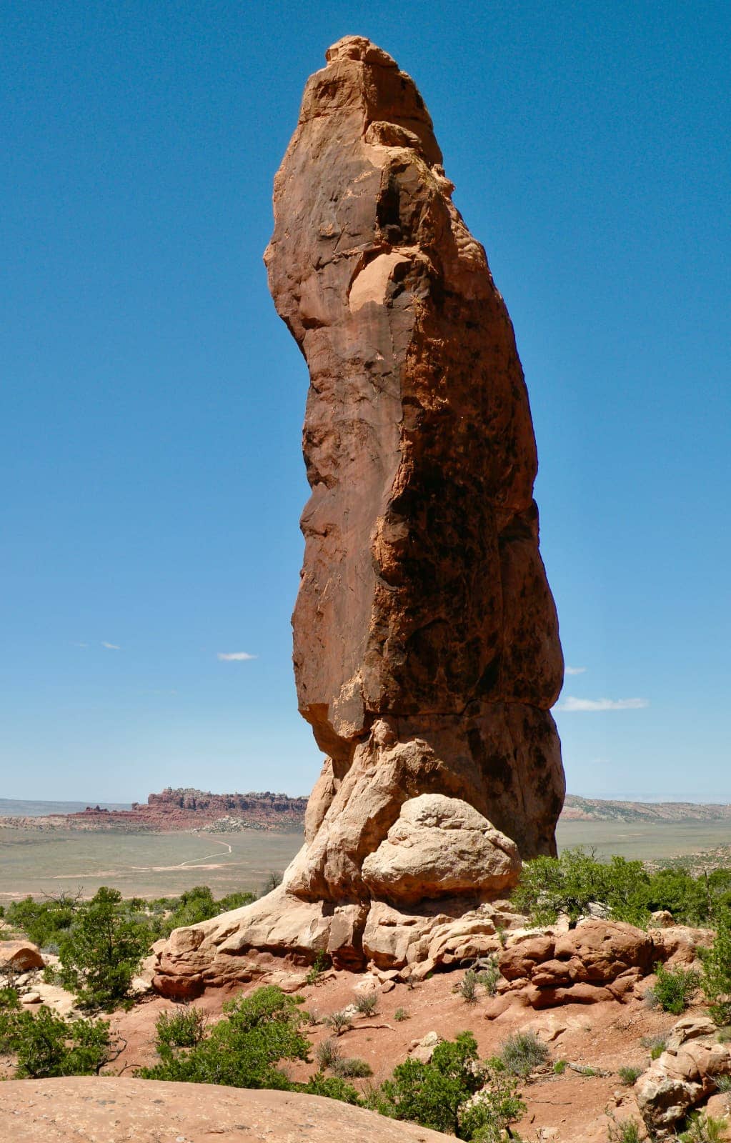 Tall and narrow rock formation in foreground with blue sky in background