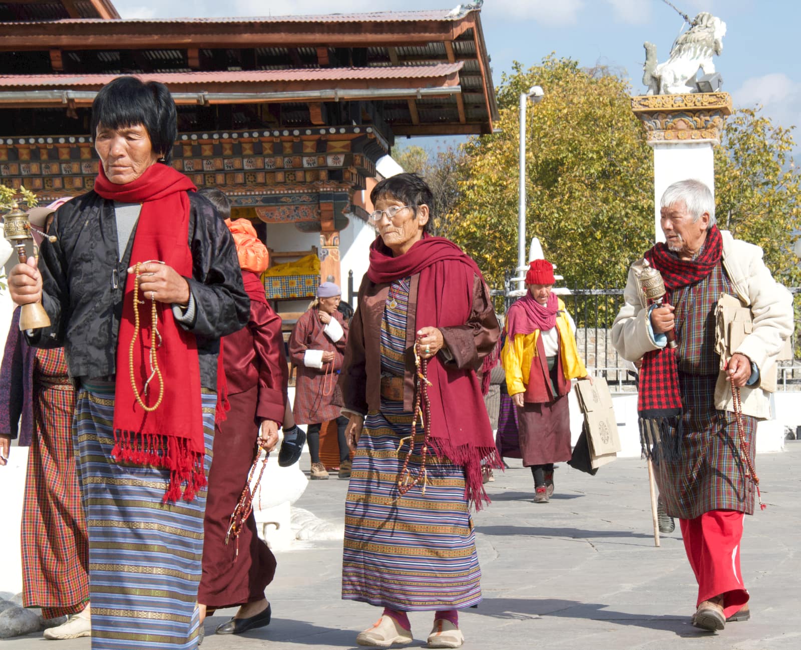 Three elderly people walking in Bhutanese clothing