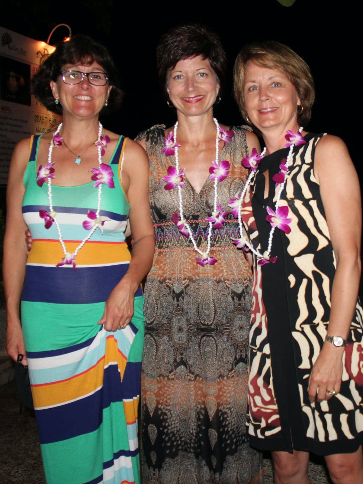 Three women in dresses posing for camera