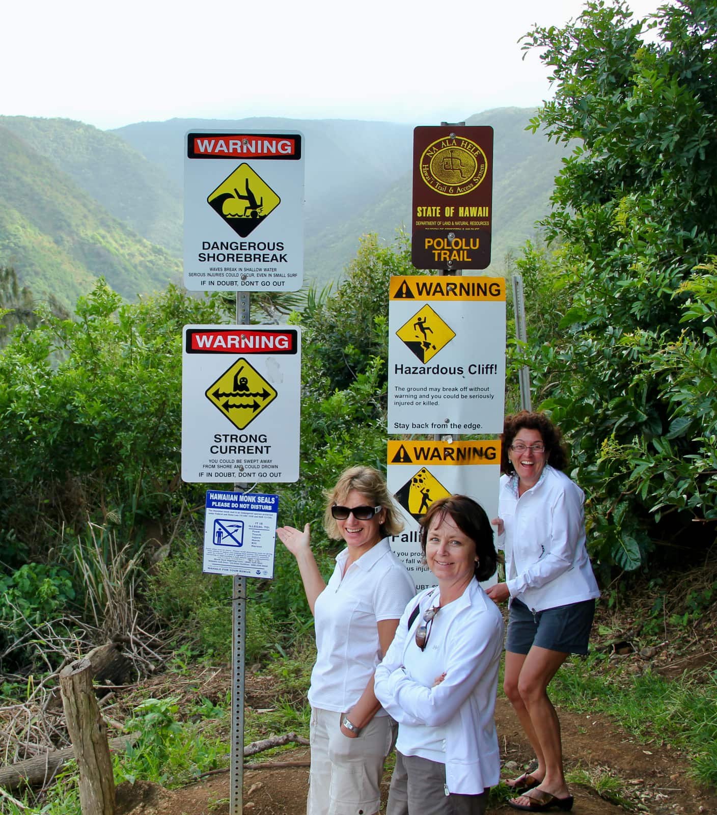 Three women standing in front of multiple hazard signs