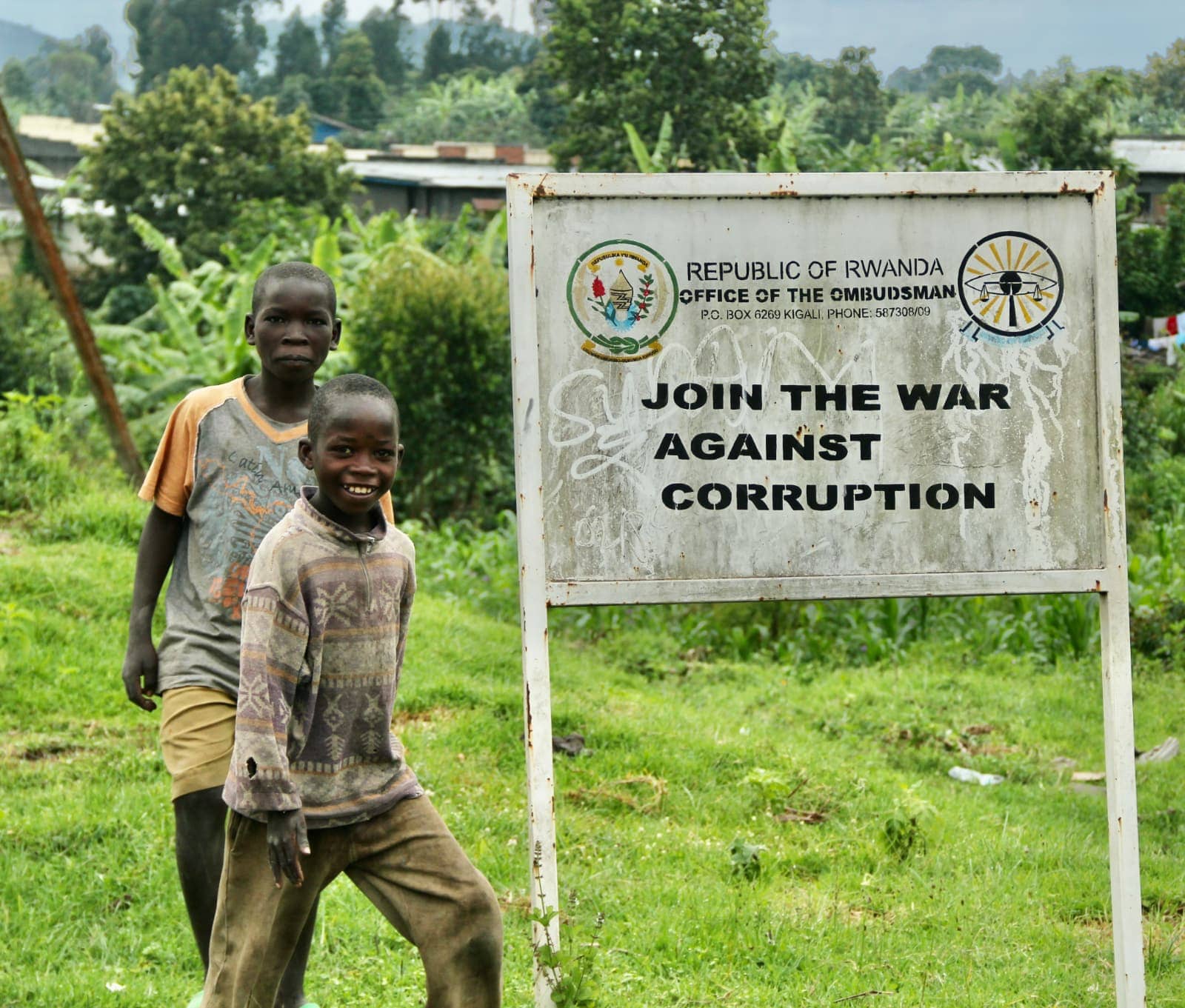 Two African children walking past anti corruption sign