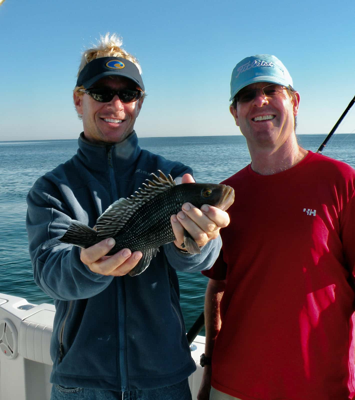 Two men smiling at camera with fish in hands