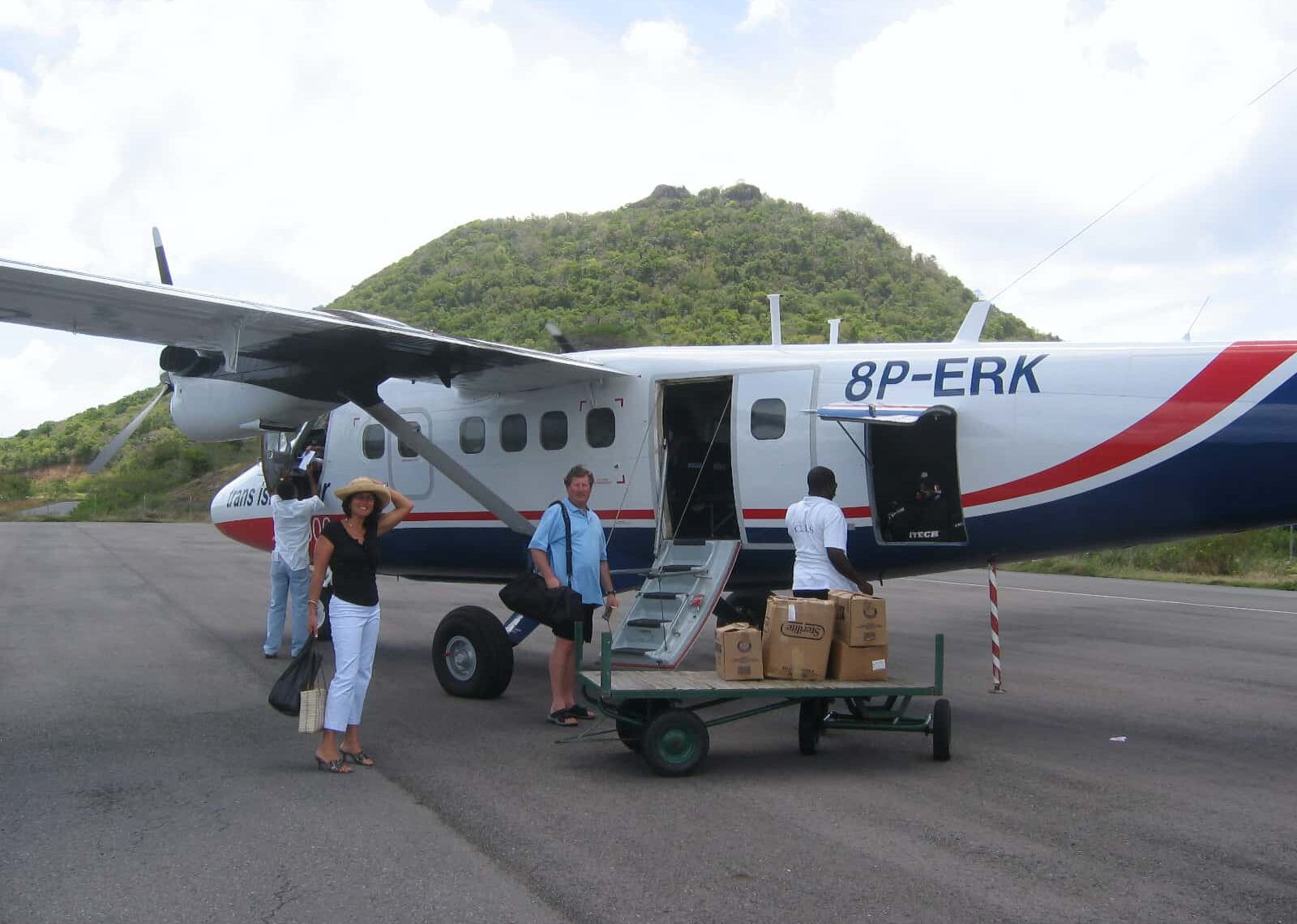 Two people boarding small white, red and blue propellor plane