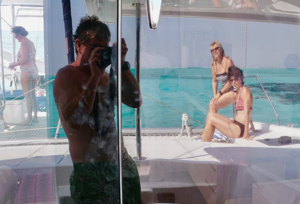 Two women being photographed on catamaran on ocean