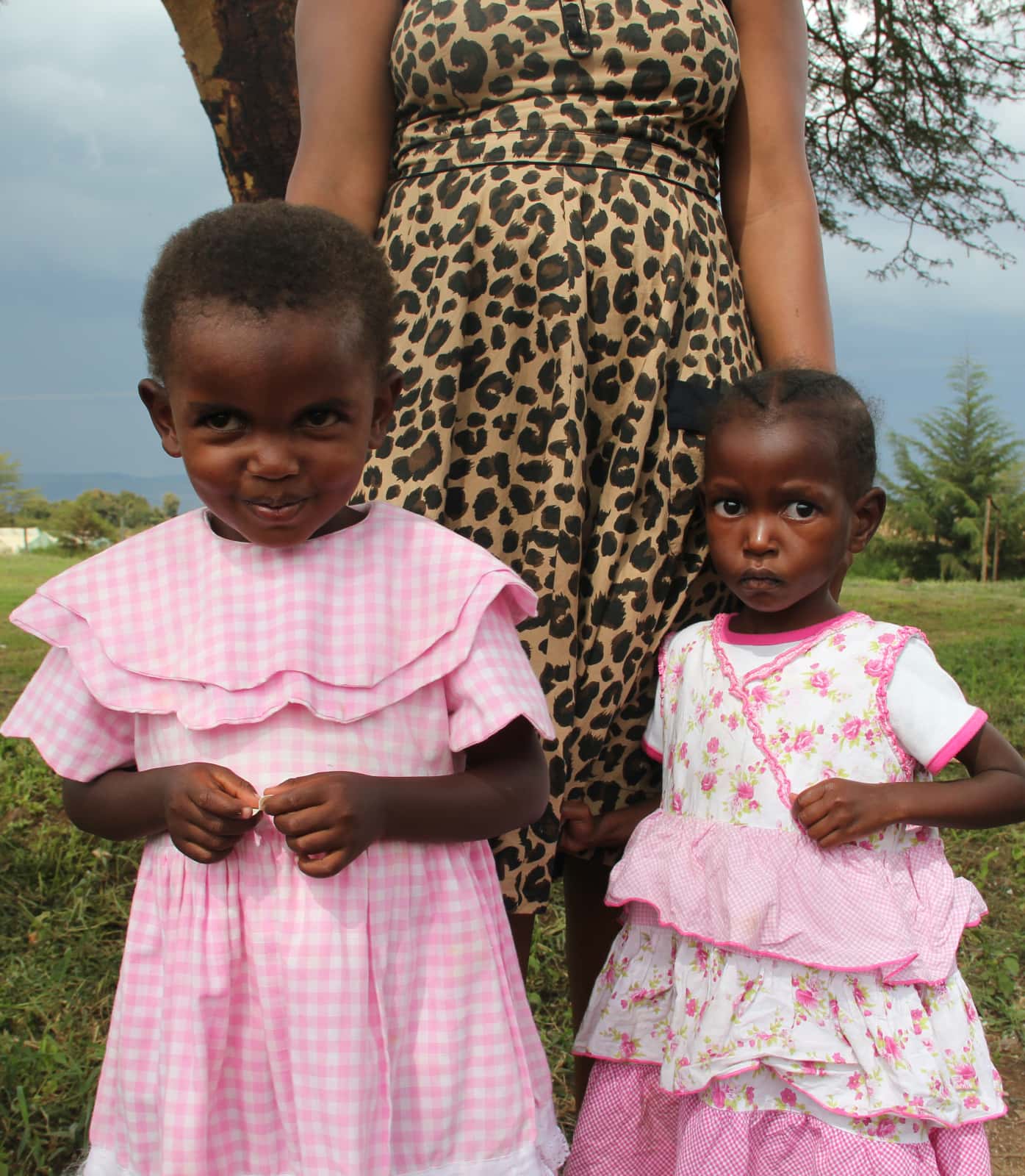 Two young African girls in pink and white dresses