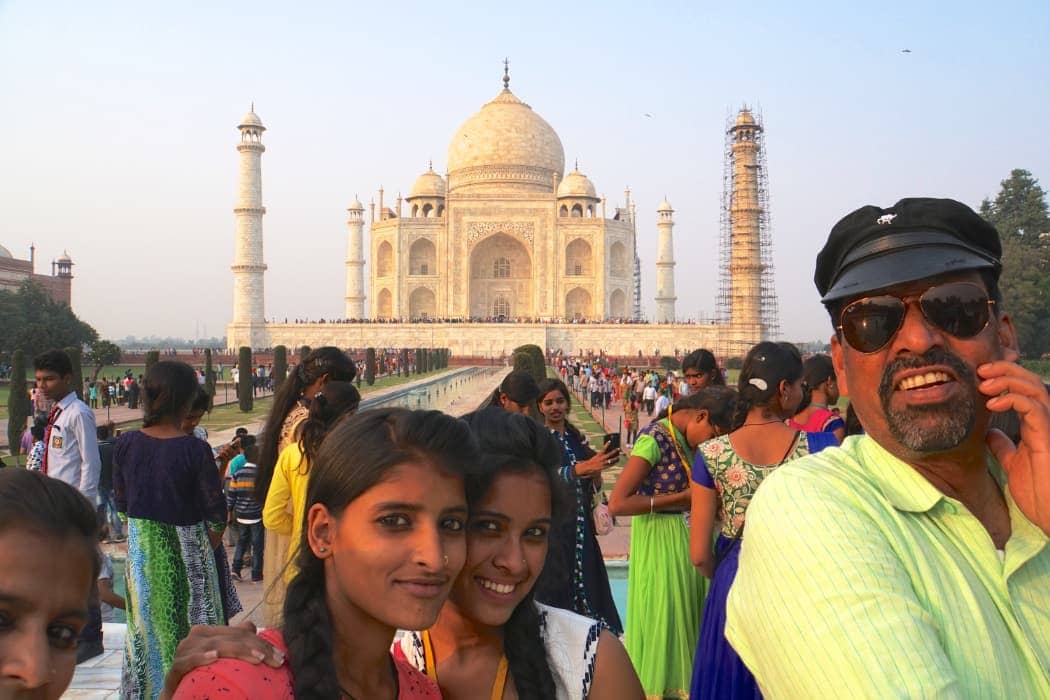 Two young women smiling at camera in front of Taj Mahal