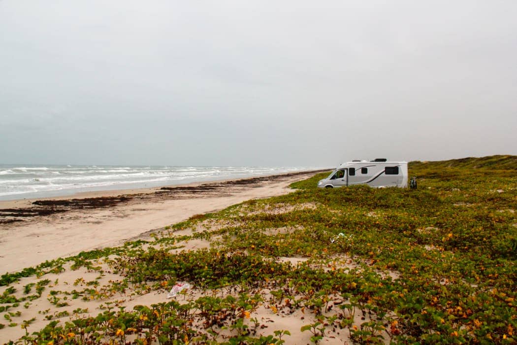 White and grey RV parked along beach