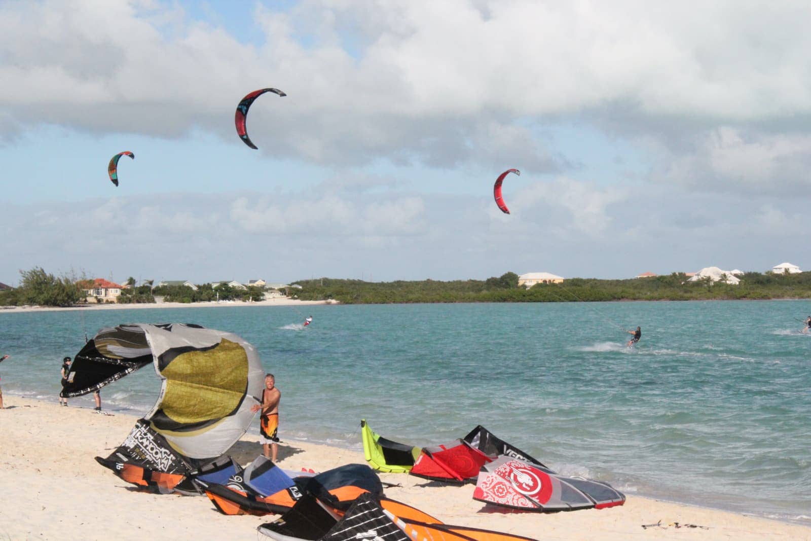 Wind surfing gear on beach in foreground with wind surfers in background