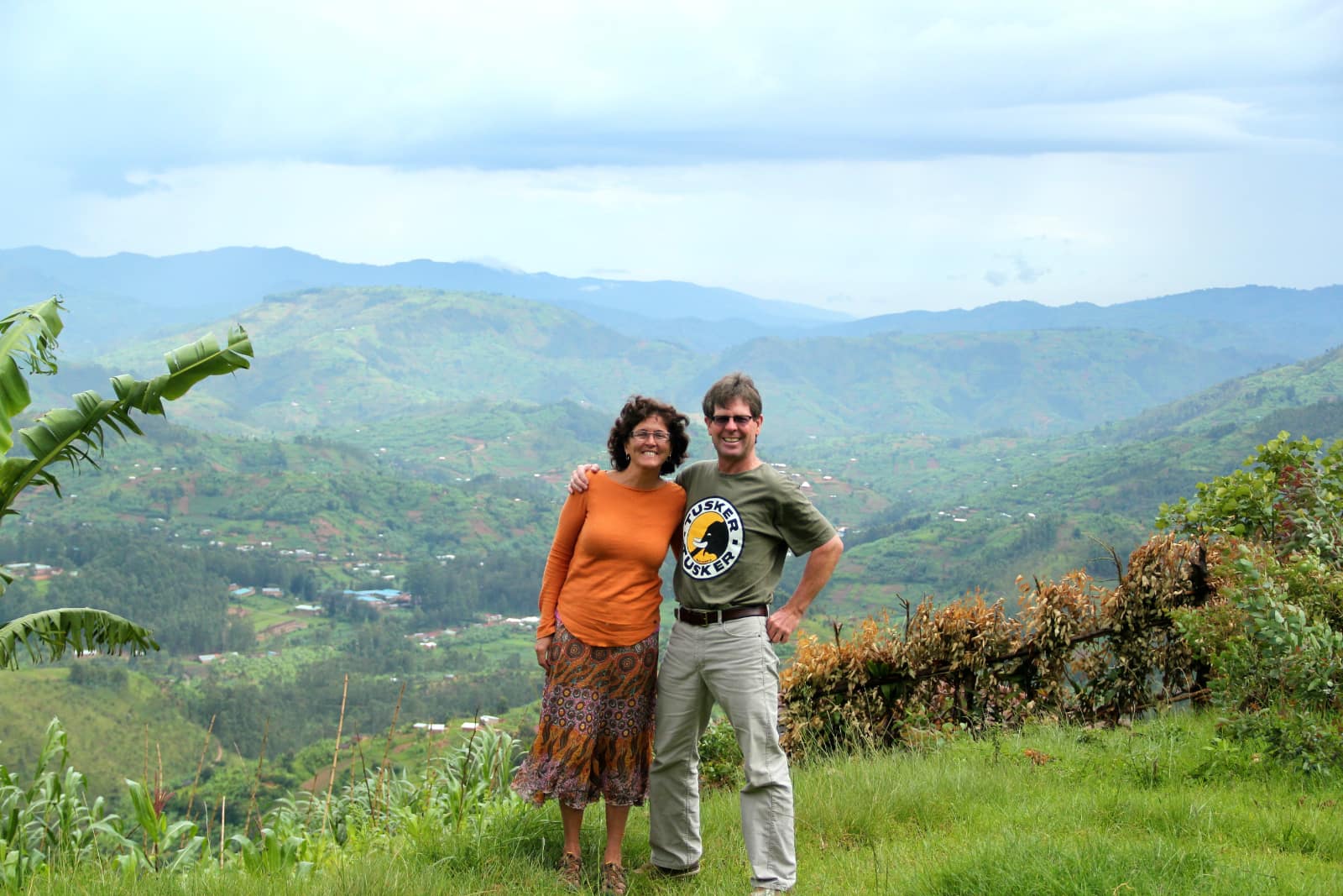 Woman and man posing in foreground with green hills in background