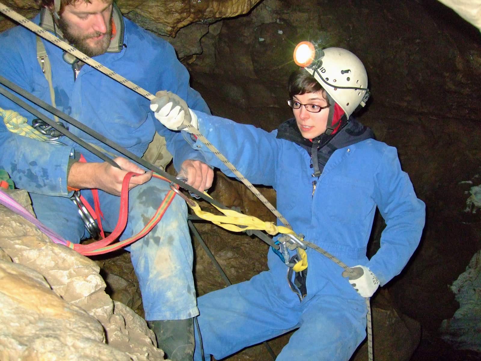 Woman and man using ropes to descend in cave