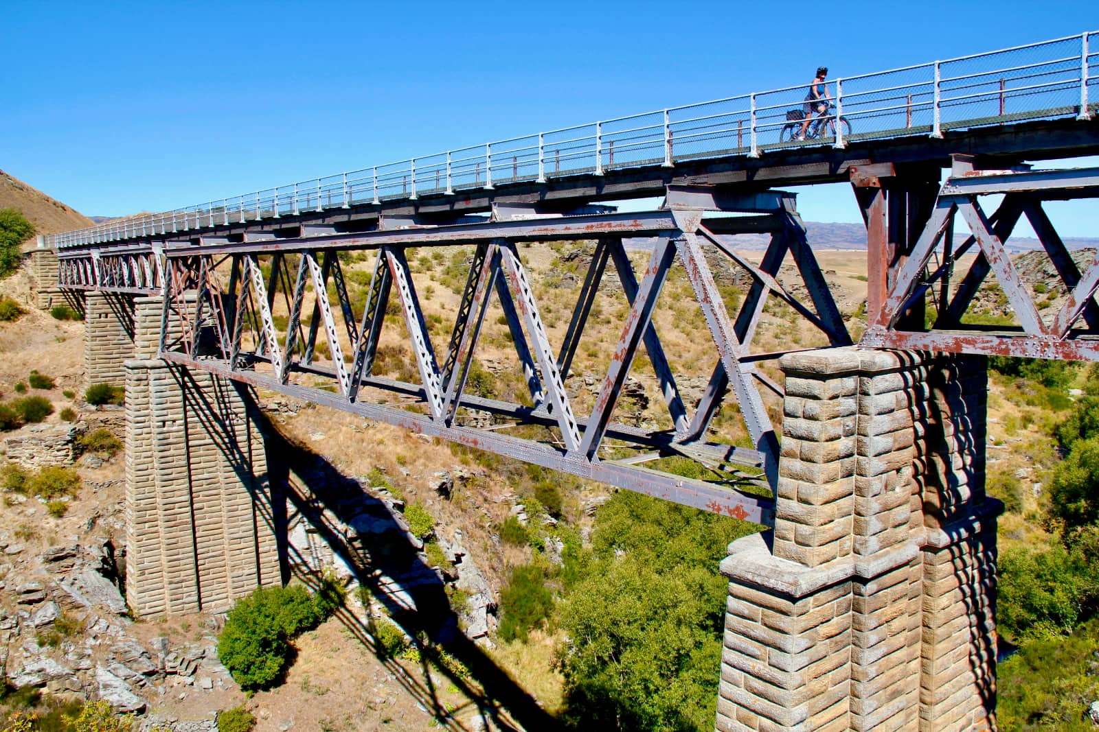 Woman cycling across large train bridge