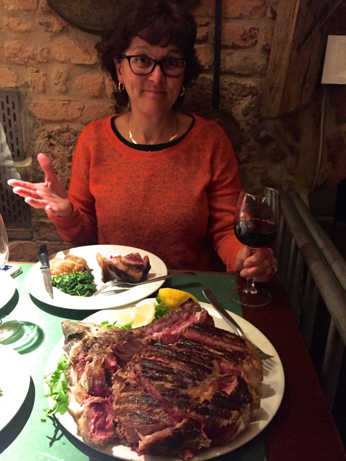 Woman enjoying meal of meat and wine