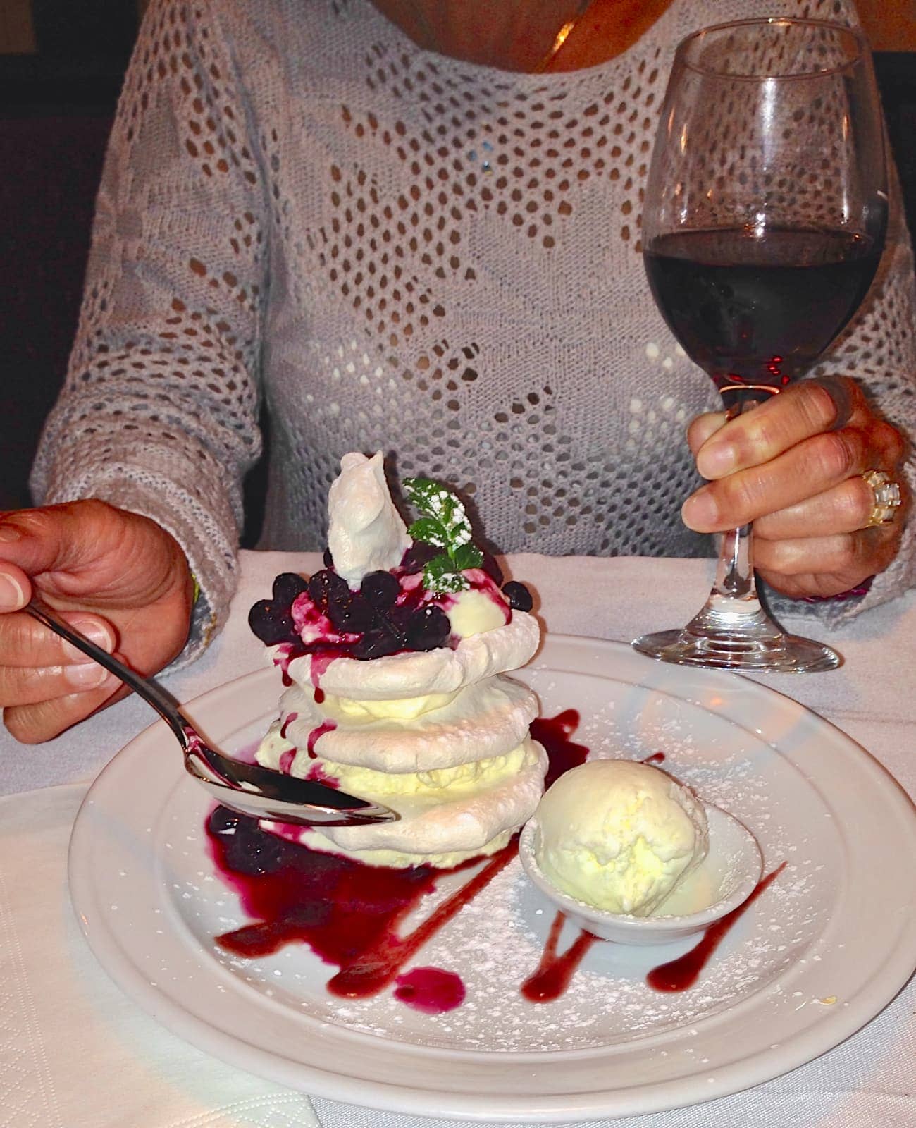 Woman enjoying Pavlova dessert and red wine