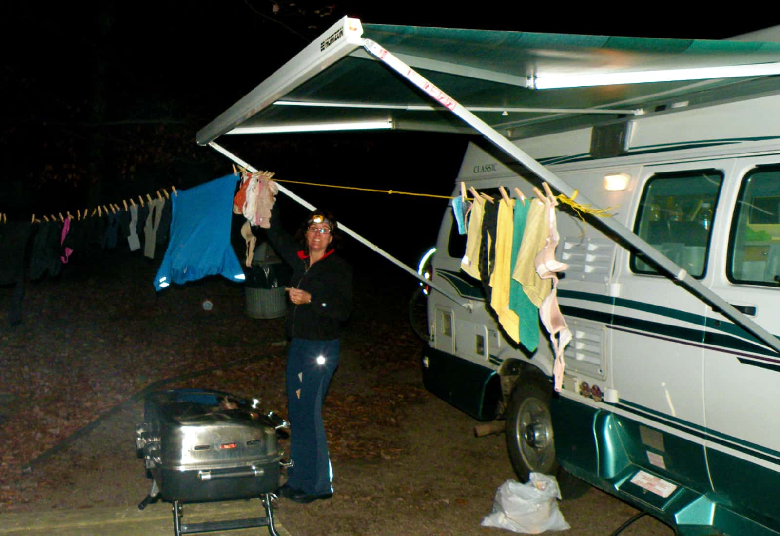 Woman hanging clothes on awning of camper van