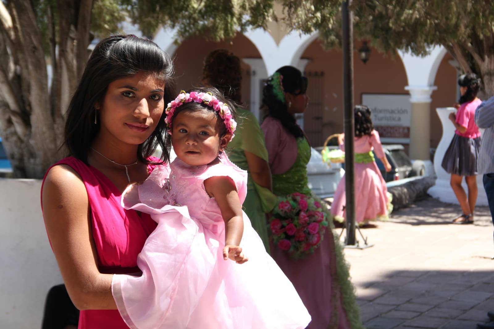 Woman in pink shirt holding young child in pink dress