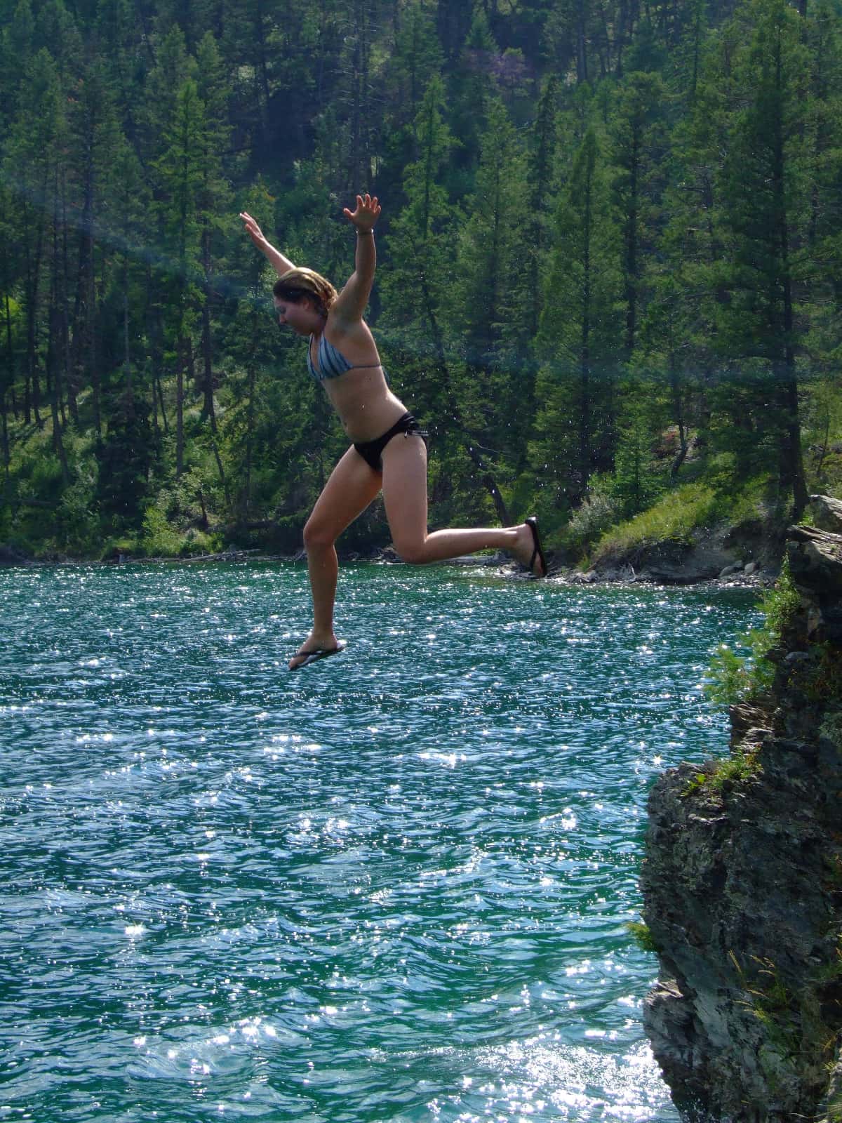 Woman jumping from rock into lake