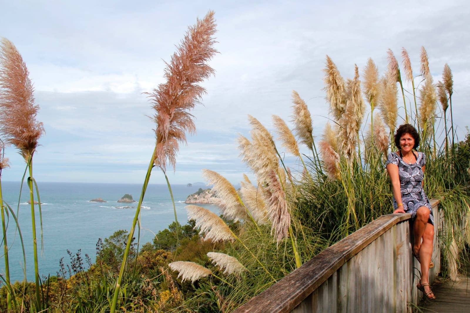 Woman posing on railing over looking ocean