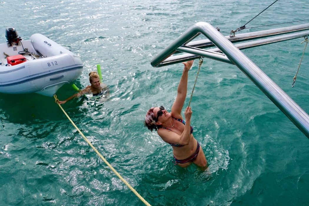 Woman reaching for boat ladder in water