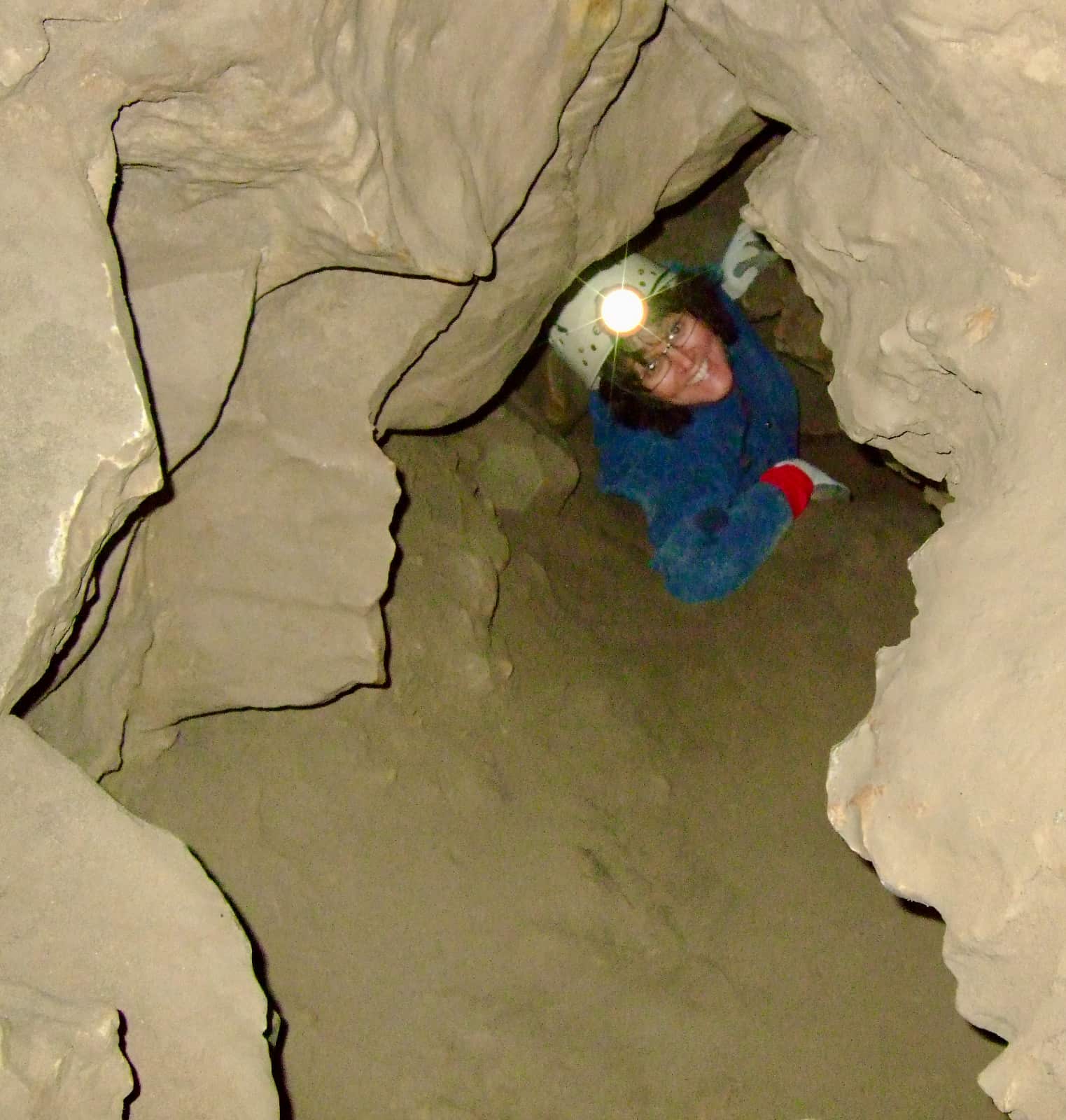 Woman smiling as she crawls through narrow cave