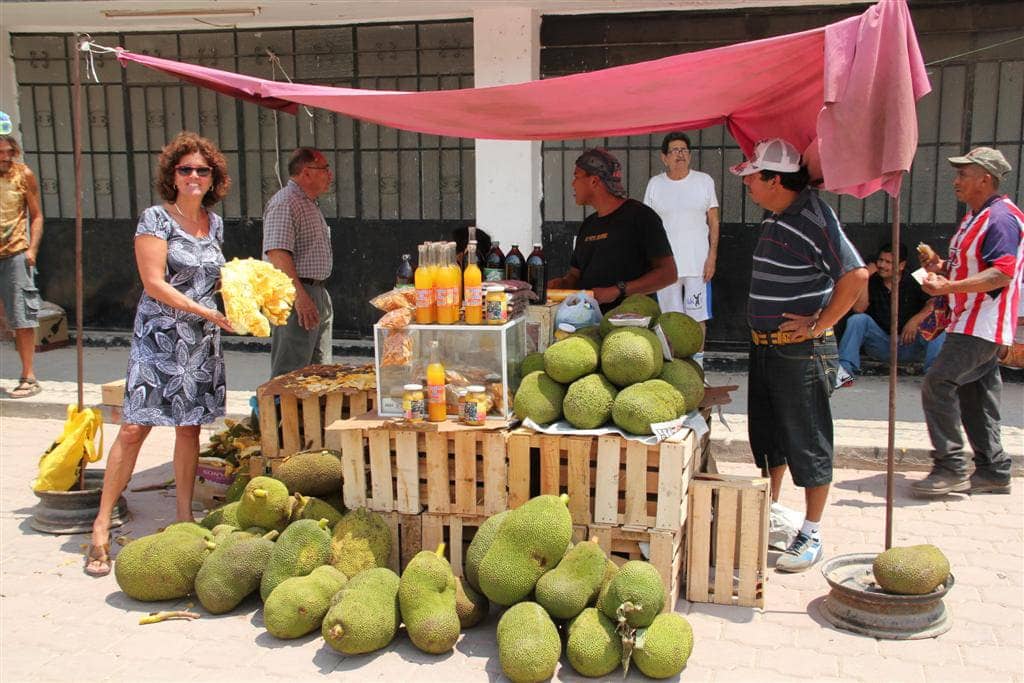 Woman standing by fruit stand with patrons walking past