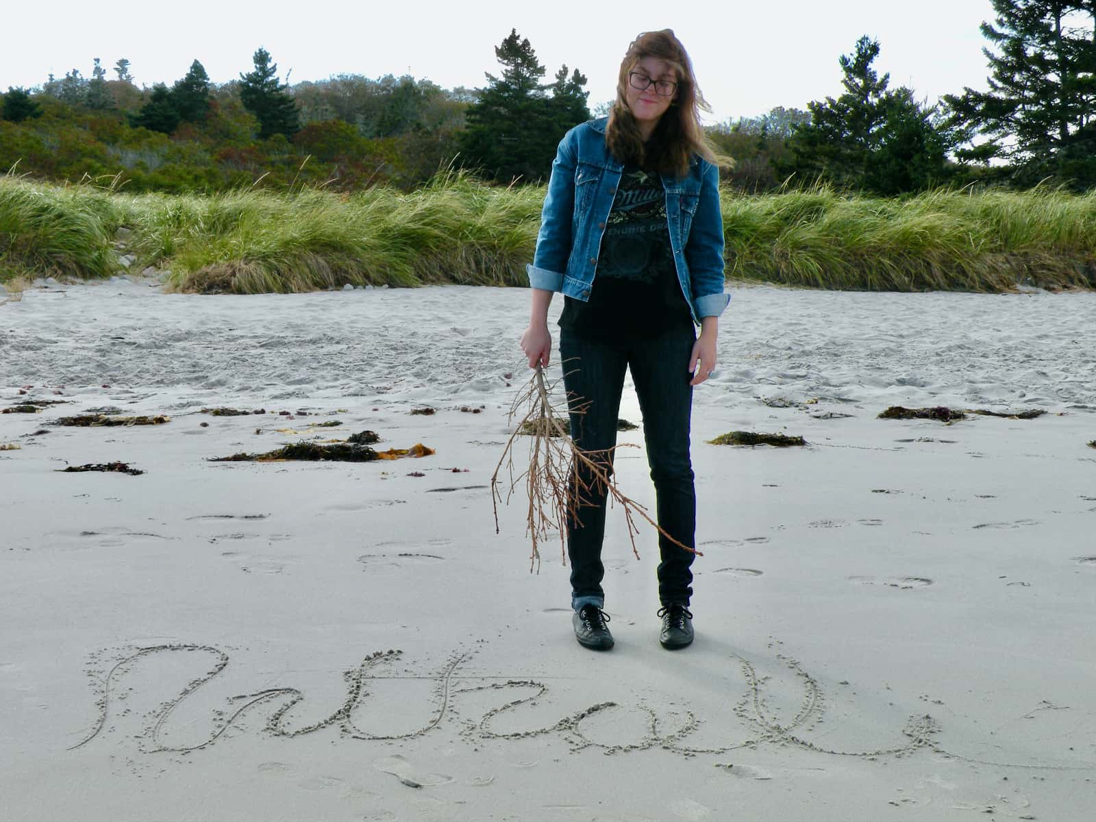 Woman standing on beach with design drawn in sand