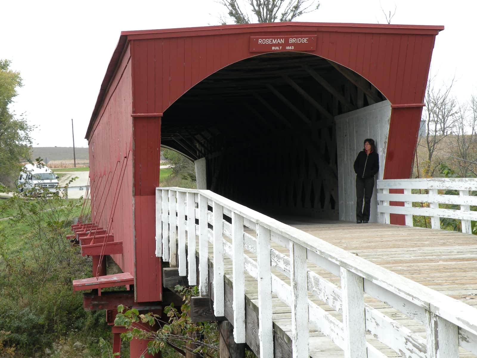 Woman standing underneath roof of red covered bridge