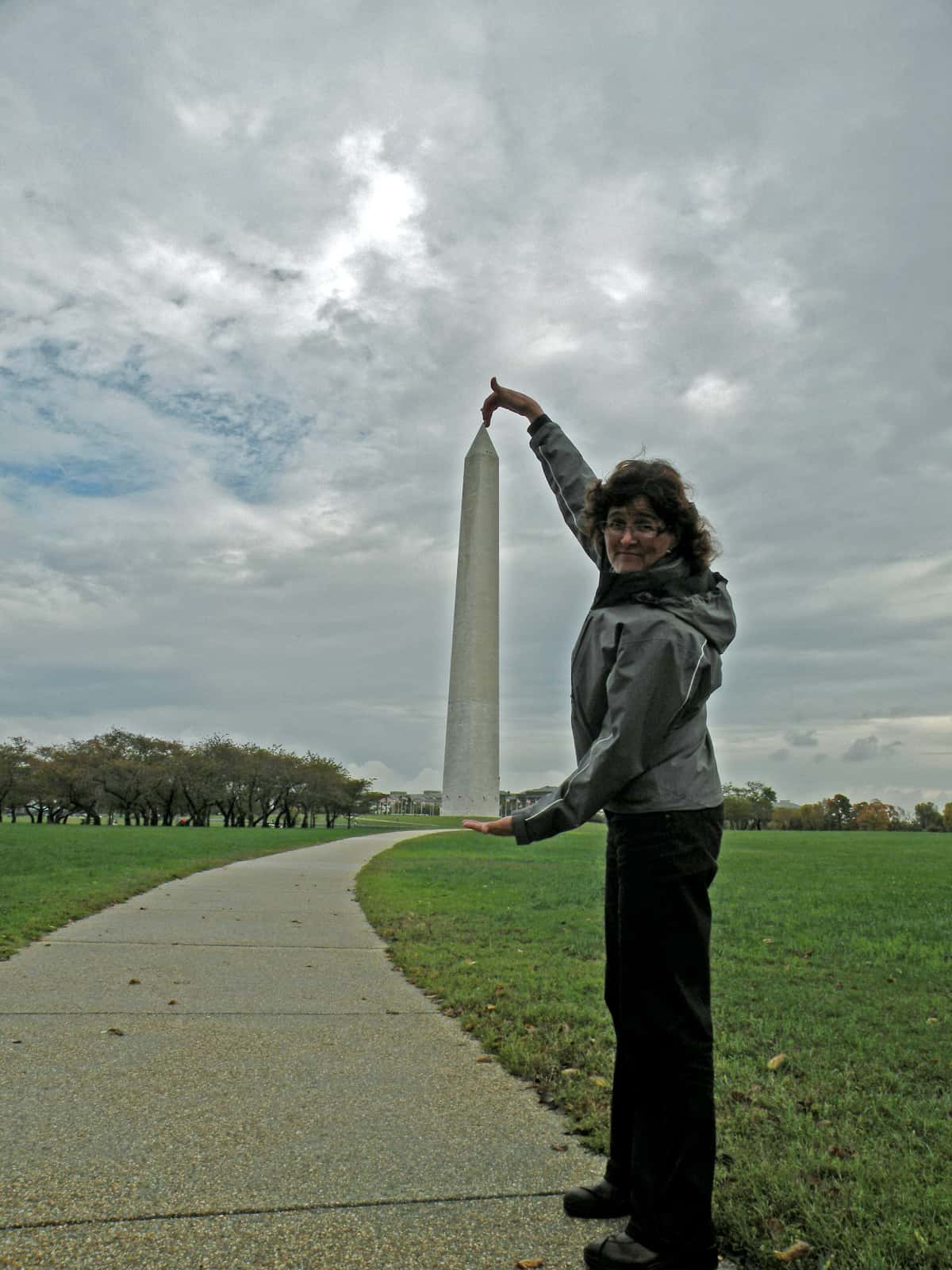 Woman standing with hands framed around Washington Monument in background