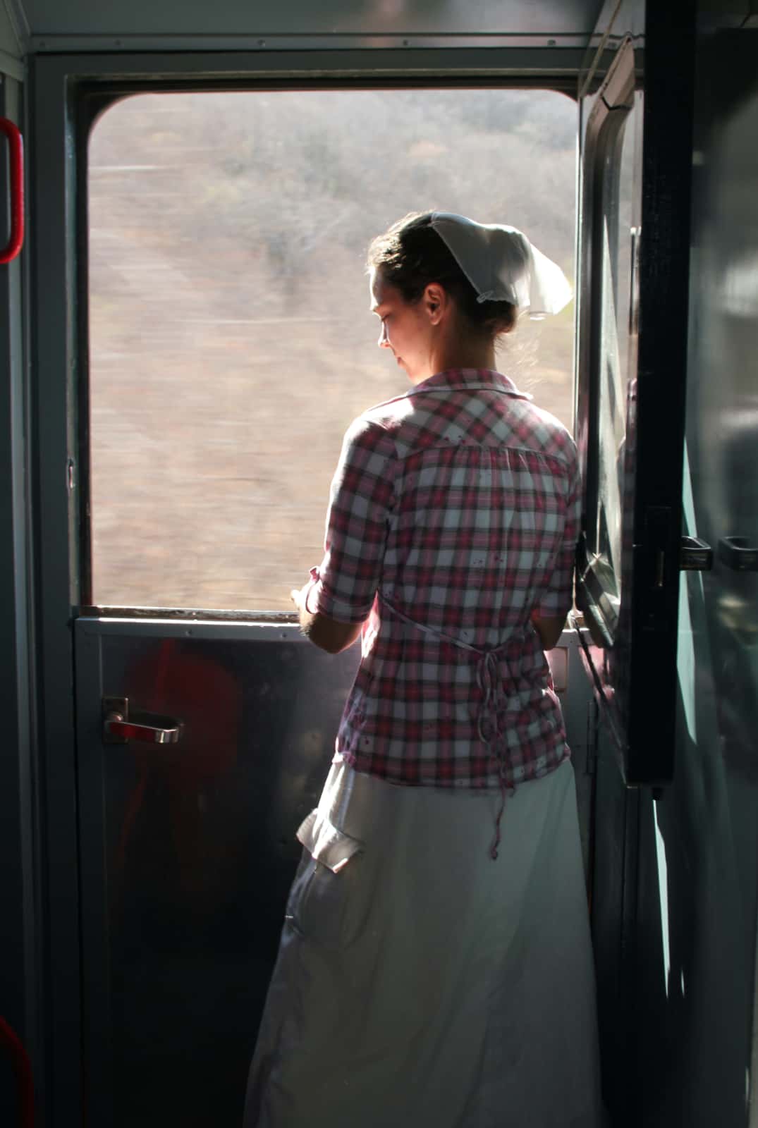 Woman standing with sunlight shining in from train window