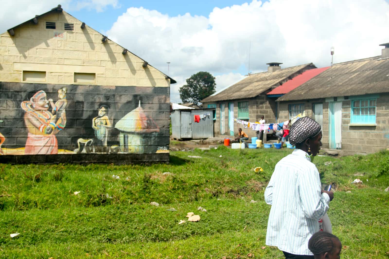 Woman walking by in foreground with stone buildings with painted murals in background