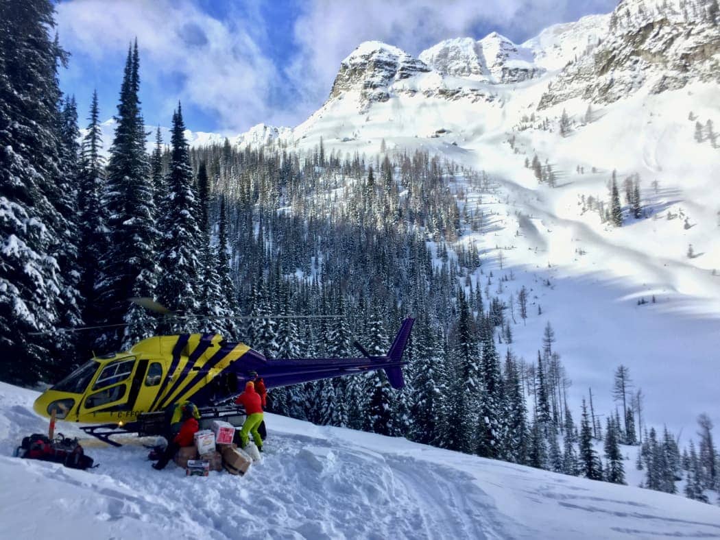 Yellow and blue helicopter loading gear in snow covered mountains