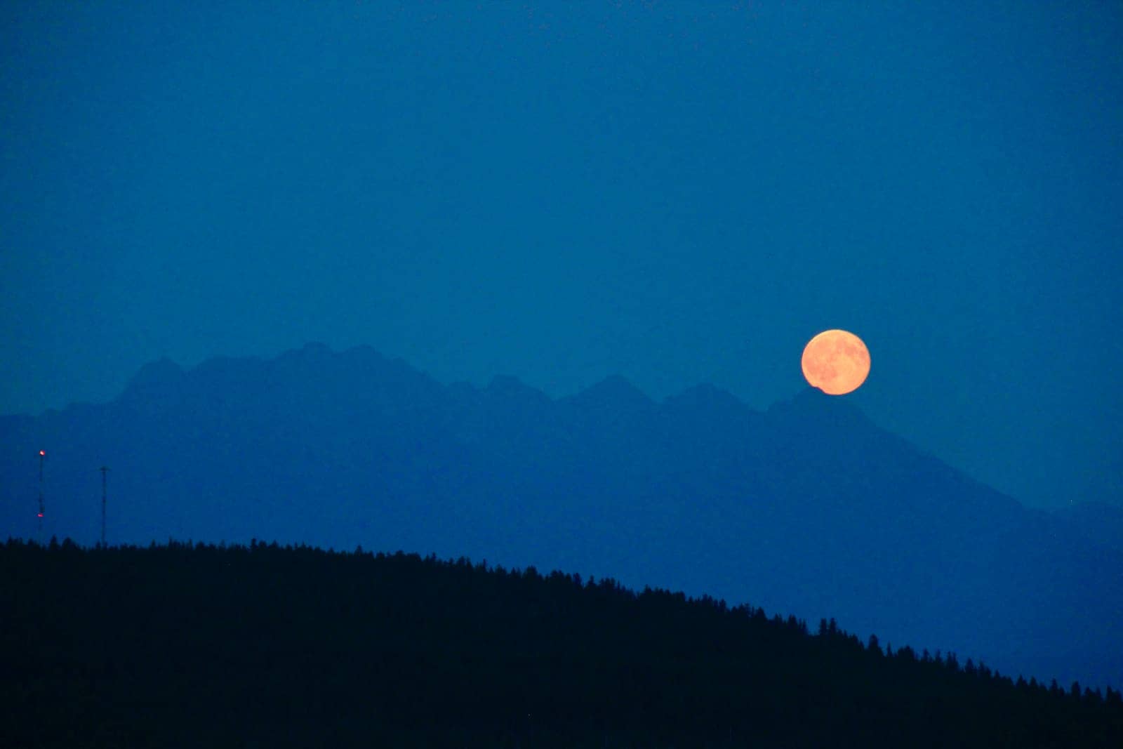 Yellow moon rising over mountains at night