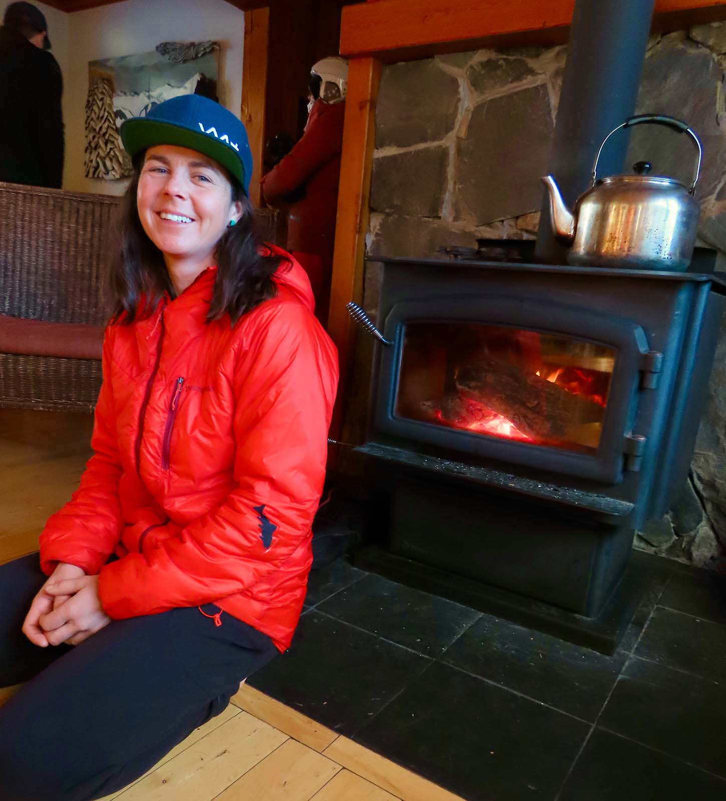 Skier seated beside indoor fireplace
