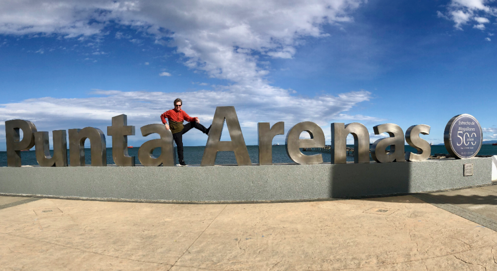 A large metal sign reading "Punta Arenas" with a man in a red jacket between the two words.