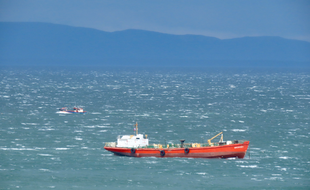 A red boat in a choppy body of water.